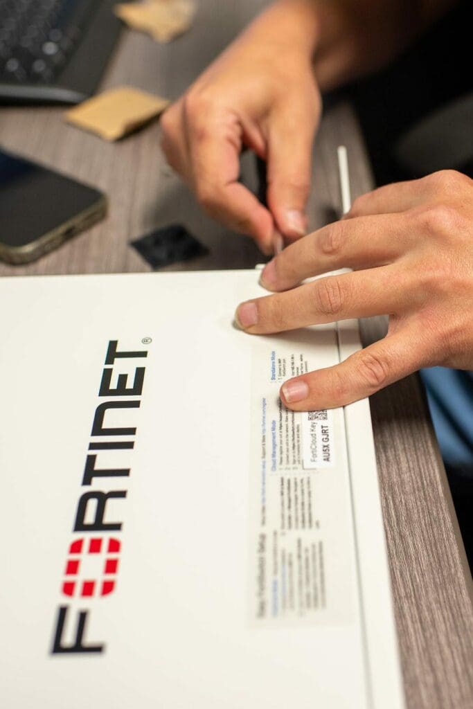 Close up photo of an Ascend associate fixing a a Fortinet box