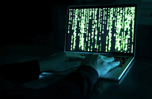 In this photo illustration, a hacker uses a computer.
